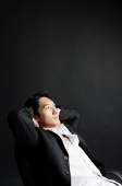 Man sitting, leaning back, hands on head - Asia Images Group