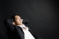 Man leaning back, hands behind head - Asia Images Group
