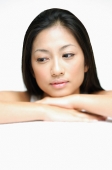 Woman resting head on hands, with downwards glance - Asia Images Group