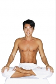 Man sitting in yoga position, smiling at camera - Asia Images Group