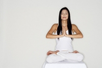 Woman practicing yoga, sitting in lotus position, hands together - Asia Images Group