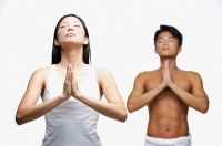 Couple doing yoga, woman in front, man standing in background - Asia Images Group