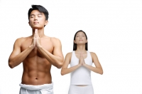 Couple doing yoga, hands together, man in front, woman standing behind him - Asia Images Group