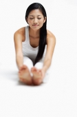 Woman doing yoga, sitting on floor, stretching, holding feet, eyes closed - Asia Images Group