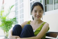 Young woman smiling at camera, hugging knees - Asia Images Group