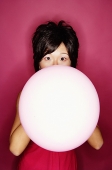 Woman blowing pink balloon - Asia Images Group