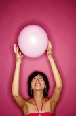 Woman tossing pink balloon - Asia Images Group