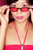 Woman adjusting sunglasses, looking at camera - Asia Images Group