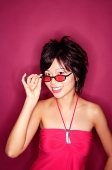 Woman adjusting sunglasses, smiling at camera - Asia Images Group