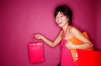 Woman carrying shopping bags, smiling at camera - Asia Images Group