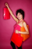 Young woman holding up shopping bags, smiling at camera - Asia Images Group