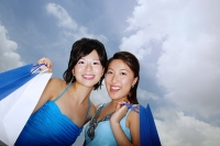 Two women standing cheek to cheek, carrying shopping bags, low angle view - Asia Images Group