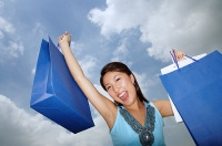 Young woman holding shopping bags, mouth open - Asia Images Group