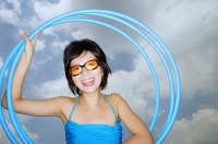 Young woman with sunglasses, holding hoola hoops - Asia Images Group