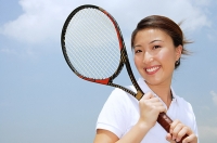 Young woman holding tennis racket, smiling at camera - Asia Images Group