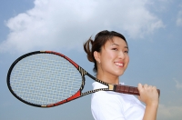Young woman holding tennis racket over shoulder, smiling at camera - Asia Images Group