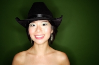 Woman wearing cowboy hat and earrings, smiling at camera - Asia Images Group
