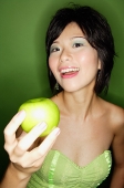 Woman holding green apple towards camera - Asia Images Group