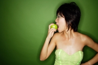 Woman biting into green apple, side view - Asia Images Group