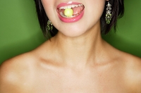 Woman eating green sweet, cropped image - Asia Images Group