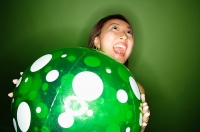 Woman holding inflatable ball, mouth open - Asia Images Group