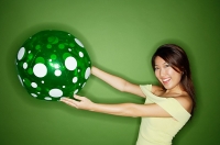 Woman holding inflatable ball, arms outstretched - Asia Images Group