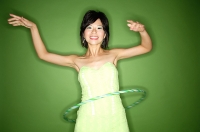 Woman in green strapless dress using hoola hoop - Asia Images Group