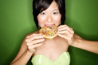Woman biting into donut - Asia Images Group