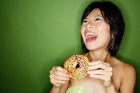 Woman holding donut, laughing - Asia Images Group