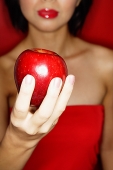 Woman in red tube tope holding red apple - Asia Images Group