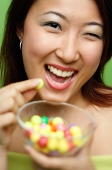 Woman holding candy and candy bowl, winking - Asia Images Group