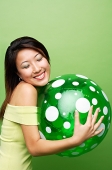 Woman hugging inflatable ball, eyes closed - Asia Images Group