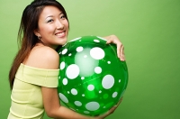 Woman embracing inflatable ball, smiling at camera - Asia Images Group