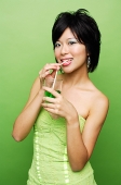 Woman drinking from glass with straw - Asia Images Group