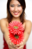 Woman holding flowers towards camera, smiling - Asia Images Group