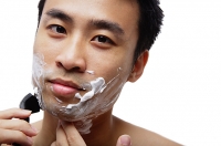 Man shaving face, looking at camera - Asia Images Group