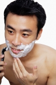 Man holding shaver, shaving face - Asia Images Group