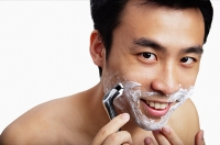 Man shaving, smiling at camera - Asia Images Group