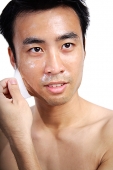 Man pulling facial mask off face - Asia Images Group