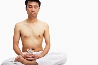 Man sitting in lotus position, eyes closed - Asia Images Group