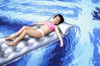 Girl lying on inflatable bed in swimming pool - Asia Images Group