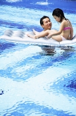Father and daughter in swimming pool, daughter on inflatable raft - Asia Images Group