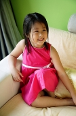 Girl sitting on sofa, smiling - Asia Images Group