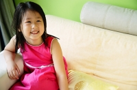 Girl on sofa, smiling - Asia Images Group