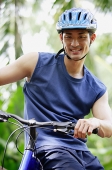 Man sitting on bicycle, looking at camera - Asia Images Group