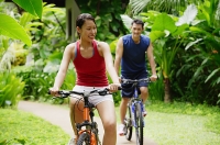 Couple cycling through a park - Asia Images Group