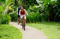 Couple cycling leisurely through a park - Asia Images Group
