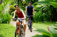 Couple cycling through a park, smiling - Asia Images Group