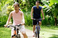 Young couple cycling through a park - Asia Images Group