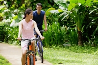 Couple cycling together through a park - Asia Images Group